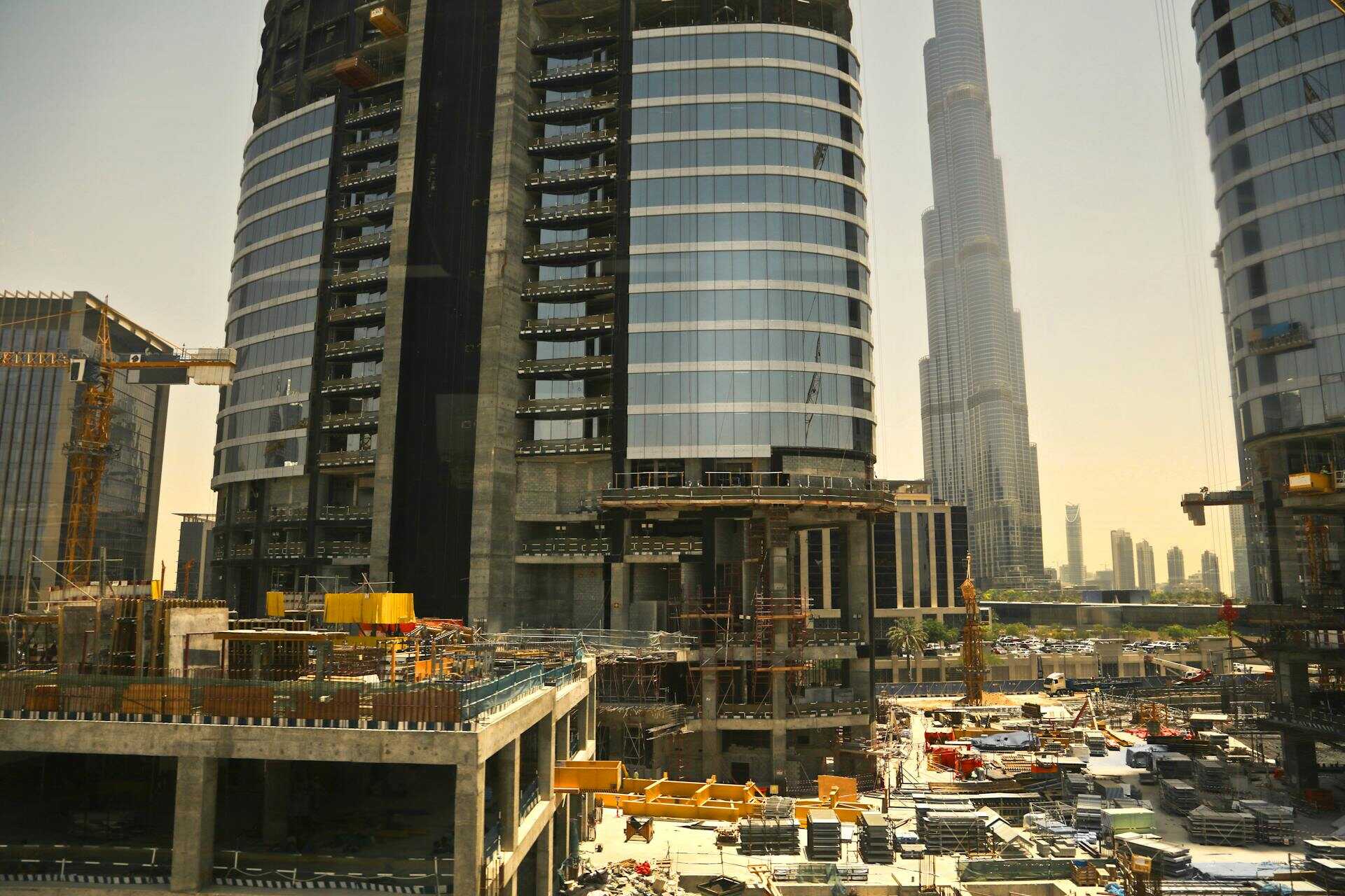 Construction site in Dubai with cranes and the Burj Khalifa skyline in the background